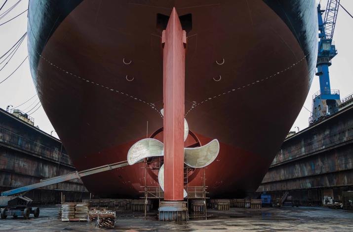 Vessel stern and propeller exposed in dry dock during hull inspection