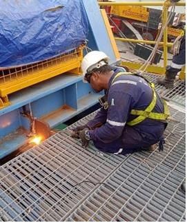 Technician carrying out hot work on deck gratings during a maintenance job